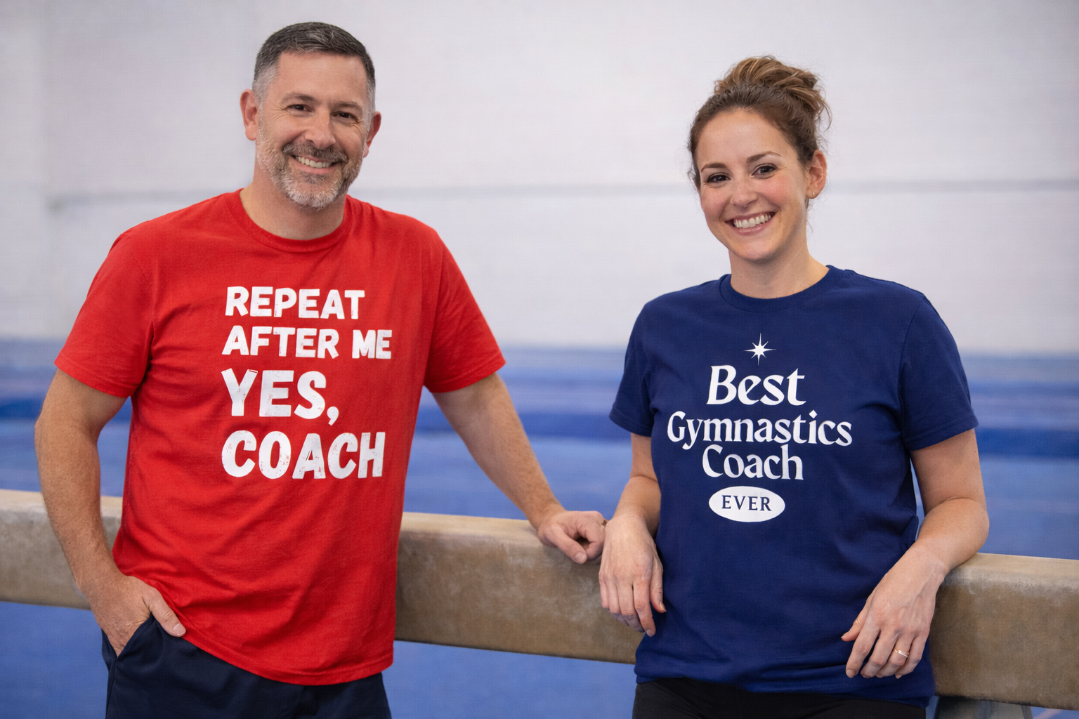 Two people wearing humorous t-shirts about a gymnastics coach in a gym setting.